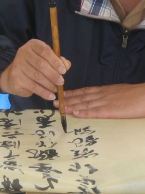 Maître Sun Fa de l'Académie Tian Long illustre la tenue du pinceau dans la calligraphie chinoise